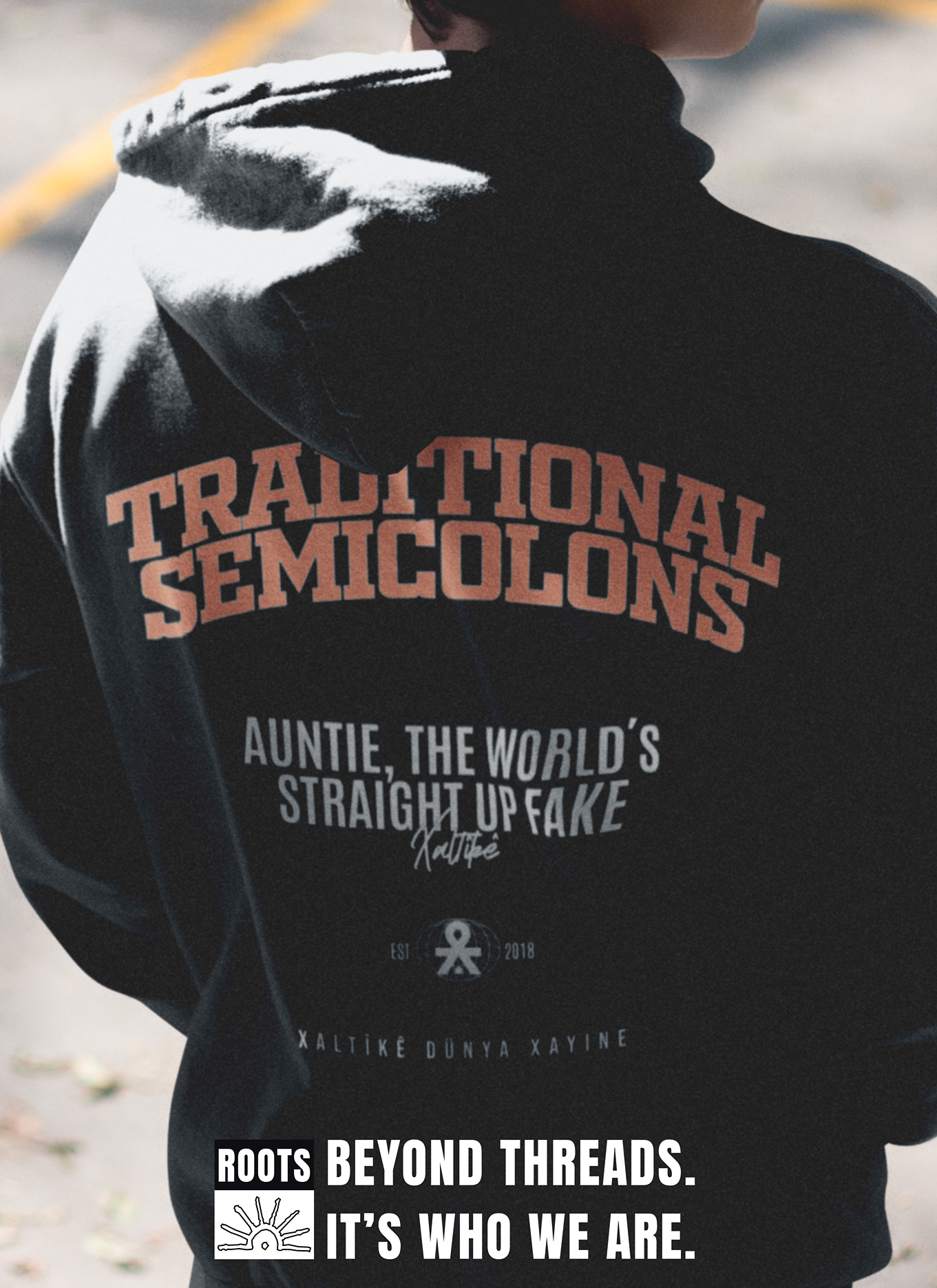 Rückansicht eines Modells mit schwarzem Xaltike-Hoodie, bedruckt mit 'Traditional Semicolons' und dem Slogan 'Roots Beyond Threads. It’s Who We Are.'