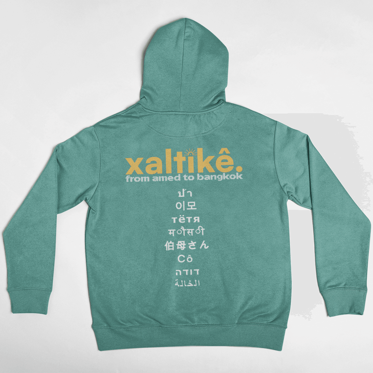 Gruener Xaltike Hoodie mit großem Backprint und internationalen Schriftzeichen, inspiriert von kurdischer Kultur.