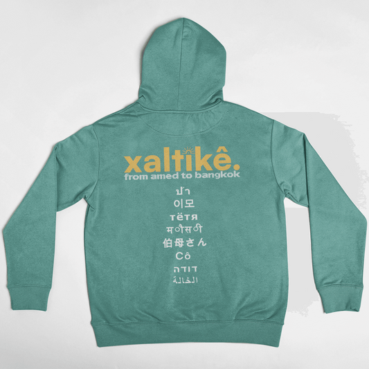 Gruener Xaltike Hoodie mit großem Backprint und internationalen Schriftzeichen, inspiriert von kurdischer Kultur.