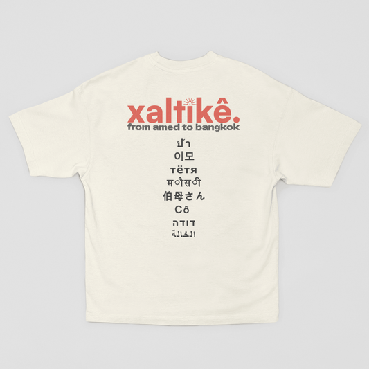 Weißes Xaltike T-Shirt mit großem Backprint und internationalen Schriftzeichen, inspiriert von kurdischer Kultur.